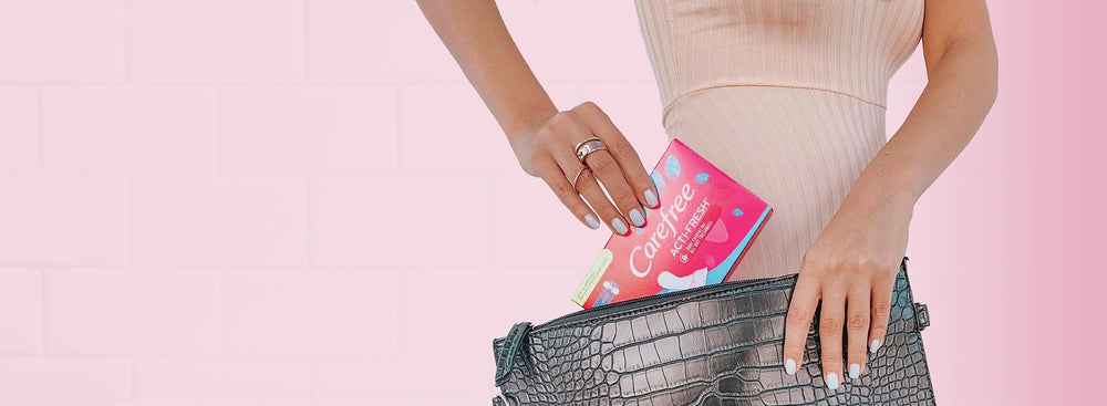 Person placing a conveinent on-the-go sized pack of Carefree Acti-Fresh liners in her bag. 